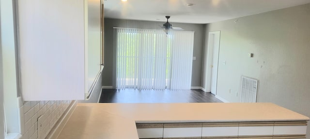 kitchen featuring dark wood-type flooring, ceiling fan, and white cabinetry