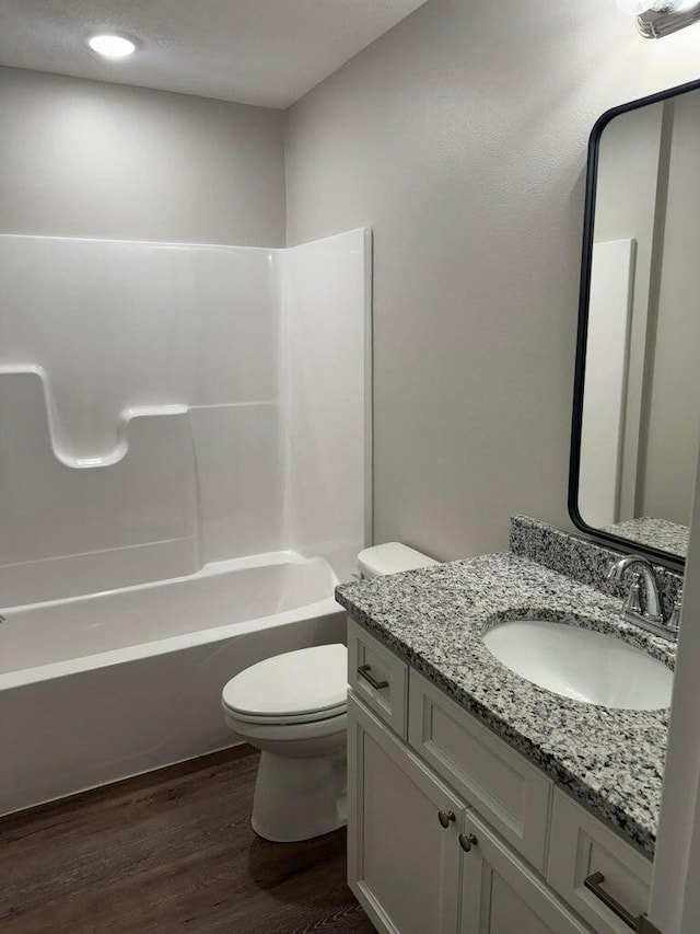 full bathroom with tub / shower combination, vanity, toilet, and hardwood / wood-style flooring