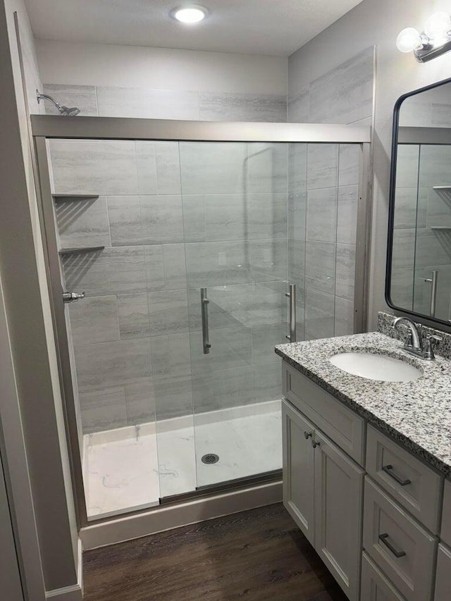 bathroom with walk in shower, hardwood / wood-style floors, and vanity