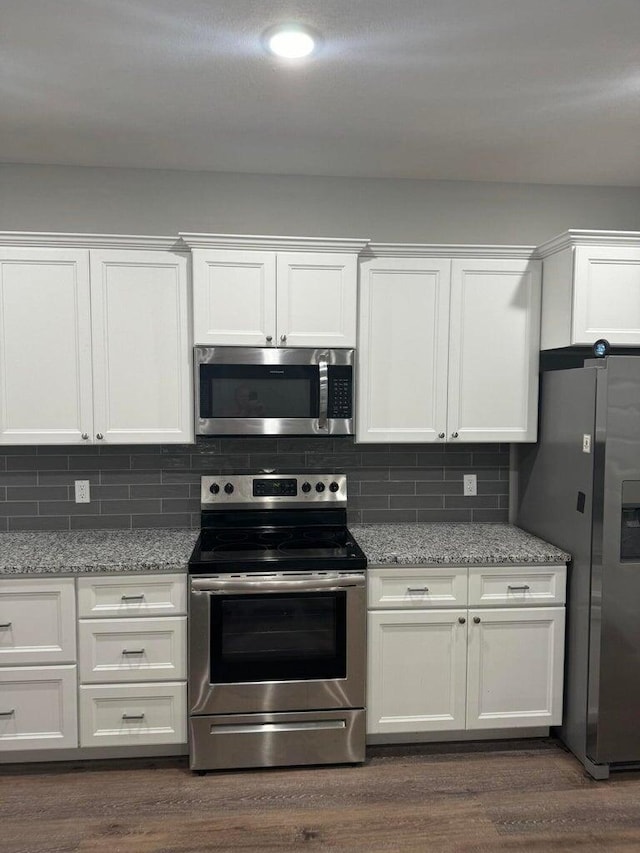 kitchen with white cabinets, stainless steel appliances, dark hardwood / wood-style flooring, and light stone countertops