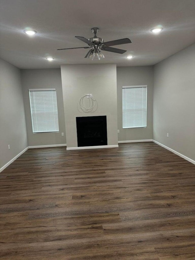 unfurnished living room with ceiling fan and dark wood-type flooring