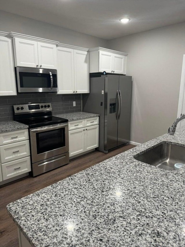 kitchen with appliances with stainless steel finishes, sink, decorative backsplash, and white cabinetry