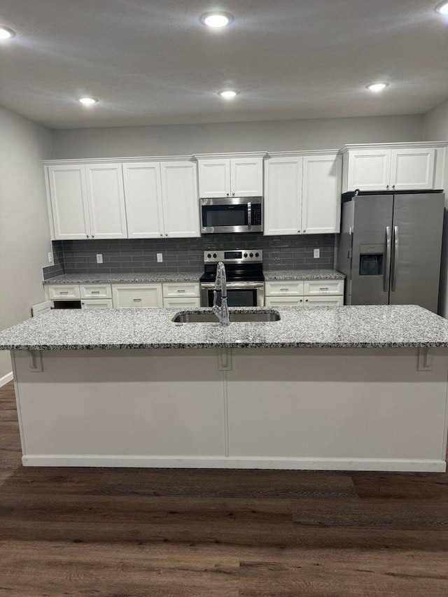 kitchen with a center island with sink, dark hardwood / wood-style floors, appliances with stainless steel finishes, and white cabinetry