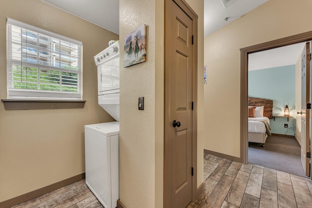 laundry area featuring light hardwood / wood-style floors and stacked washer and clothes dryer