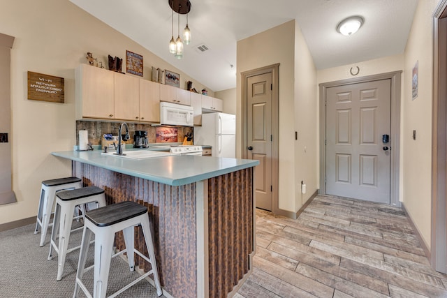 kitchen with light hardwood / wood-style floors, pendant lighting, white appliances, lofted ceiling, and kitchen peninsula