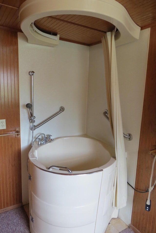 bathroom featuring wooden walls, a bathing tub, and wooden ceiling