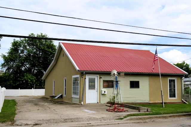 view of front of house with metal roof, stucco siding, and fence