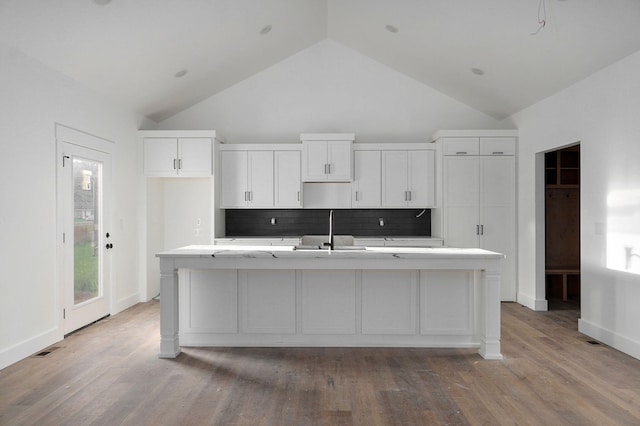 kitchen with hardwood / wood-style flooring, decorative backsplash, sink, and an island with sink