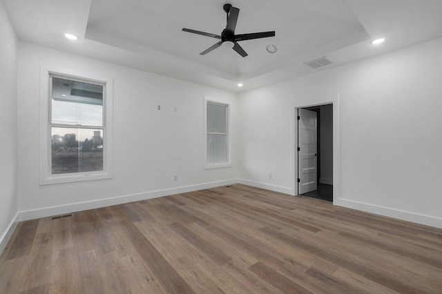 unfurnished room featuring a tray ceiling, light hardwood / wood-style flooring, and ceiling fan