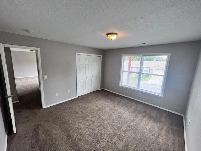 unfurnished bedroom featuring a closet, dark carpet, and a textured ceiling