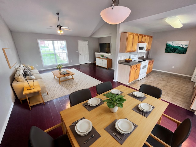 dining space featuring ceiling fan, dark hardwood / wood-style floors, and vaulted ceiling