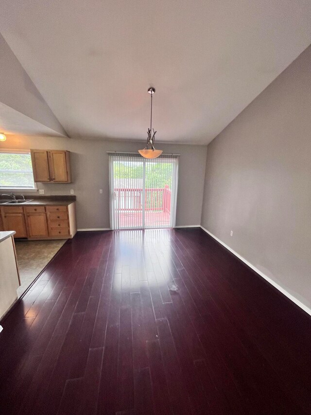 interior space with hanging light fixtures, vaulted ceiling, dark hardwood / wood-style flooring, and a healthy amount of sunlight