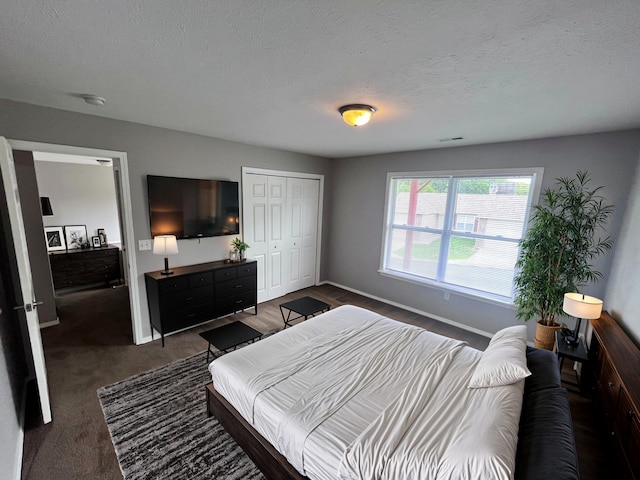 bedroom with a closet, dark colored carpet, and a textured ceiling