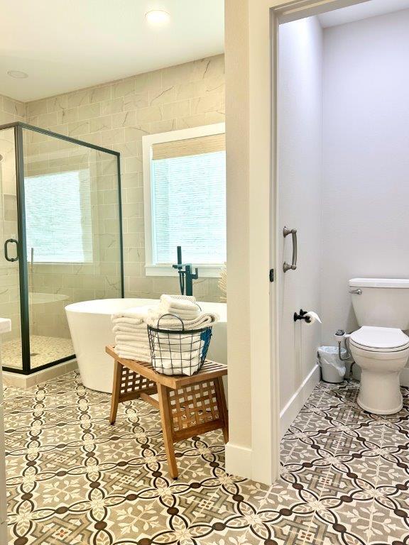 bathroom with plus walk in shower, tile patterned flooring, and toilet