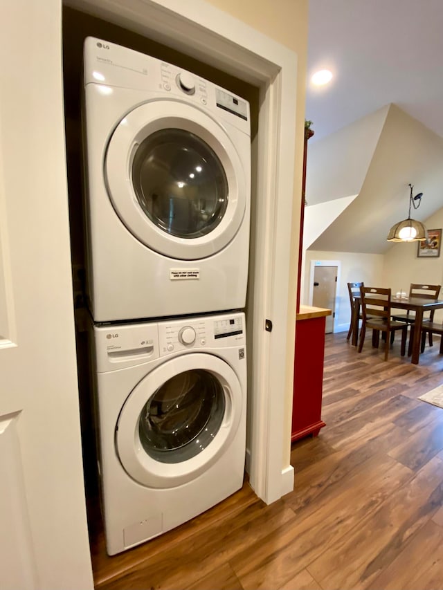 laundry room featuring stacked washer and dryer and dark hardwood / wood-style floors