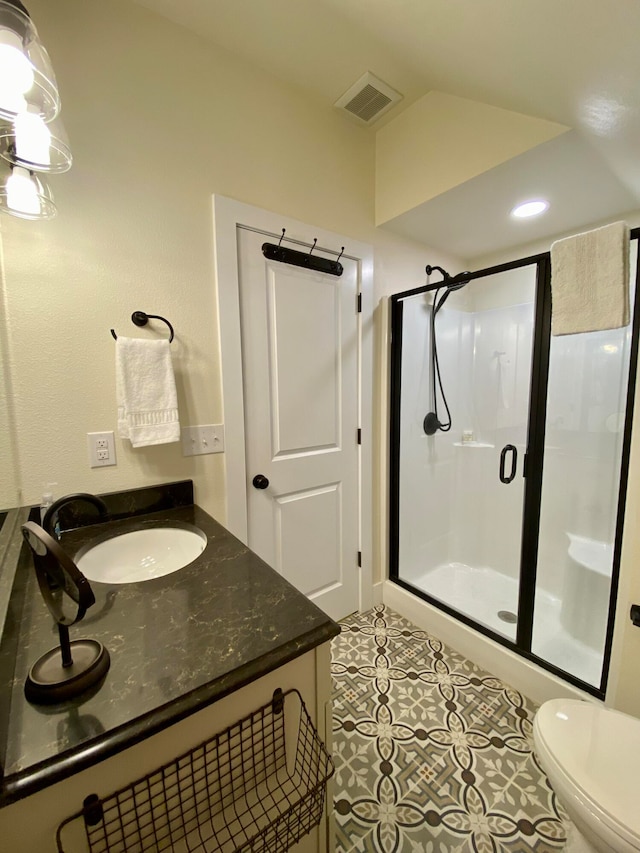 bathroom with vanity, tile patterned flooring, toilet, and an enclosed shower