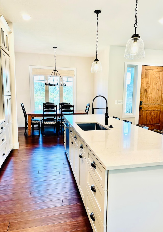 kitchen with pendant lighting, a center island with sink, dark wood-type flooring, and sink