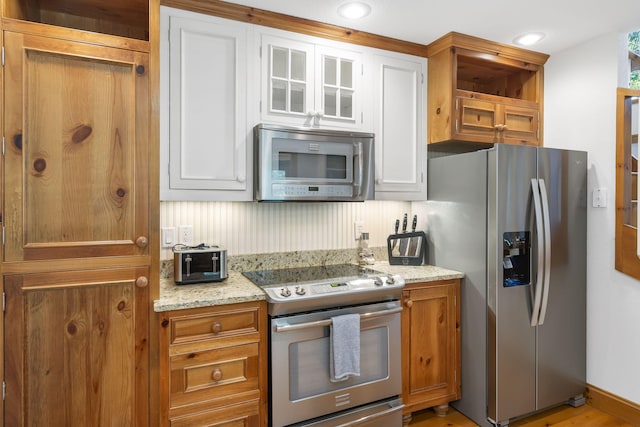 kitchen with white cabinets, appliances with stainless steel finishes, and light stone counters