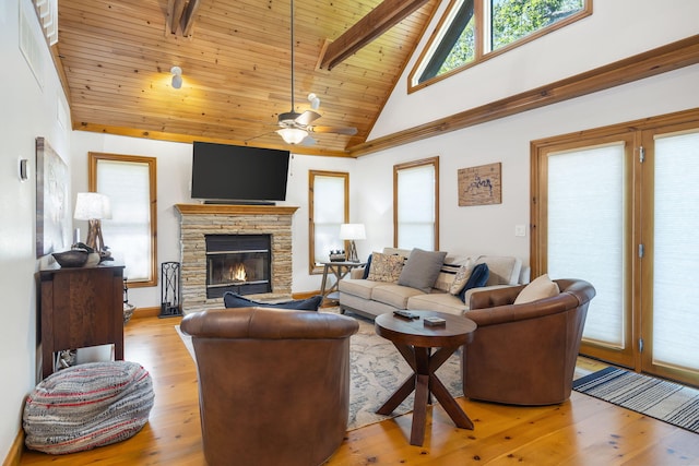 living room with ceiling fan, a stone fireplace, high vaulted ceiling, wooden ceiling, and light wood-type flooring