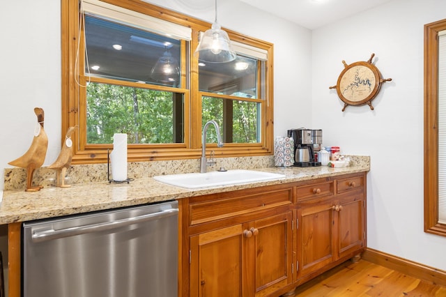 bar featuring light wood-type flooring, sink, stainless steel dishwasher, decorative light fixtures, and light stone countertops