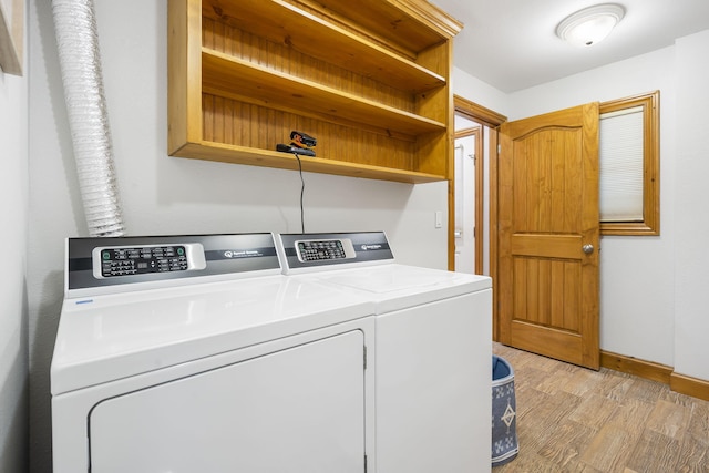 clothes washing area featuring washing machine and clothes dryer and light hardwood / wood-style floors