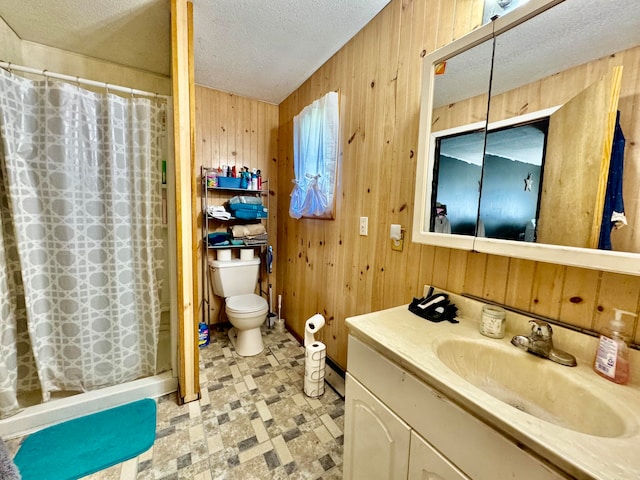 bathroom with vanity, a shower with shower curtain, wood walls, toilet, and a textured ceiling