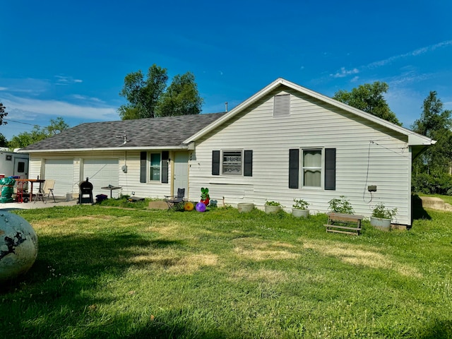 rear view of house featuring a garage and a yard