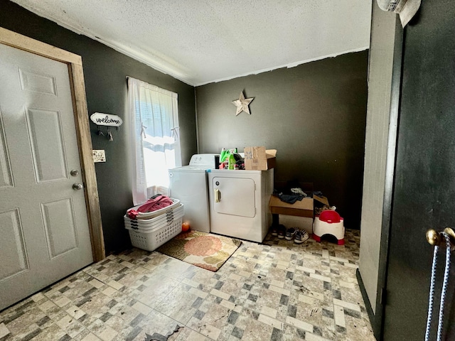 clothes washing area with washer and clothes dryer and a textured ceiling