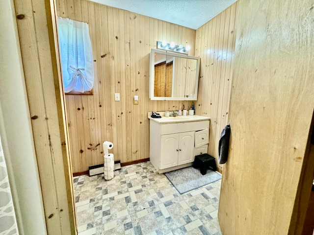 bathroom featuring vanity, wood walls, a baseboard radiator, and a textured ceiling