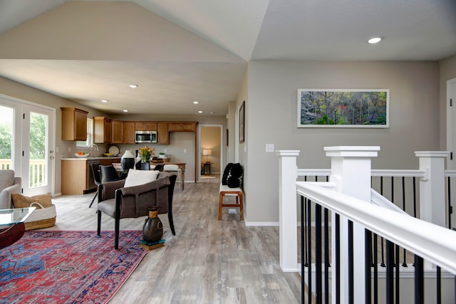 living room featuring light hardwood / wood-style floors, sink, and vaulted ceiling