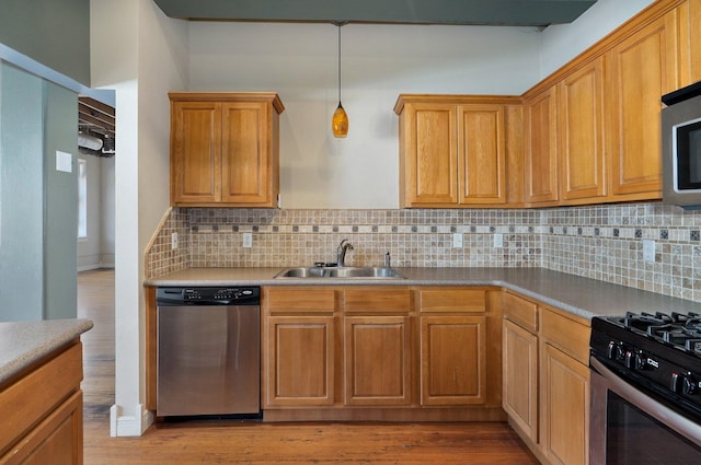 kitchen featuring stainless steel appliances, light hardwood / wood-style flooring, decorative backsplash, and sink