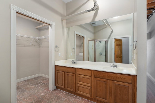 bathroom featuring washer / dryer, walk in shower, and vanity