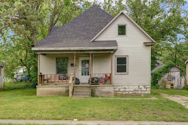 view of front of property with a front yard, a storage shed, and a porch