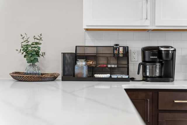 room details featuring dark brown cabinets, backsplash, and white cabinetry