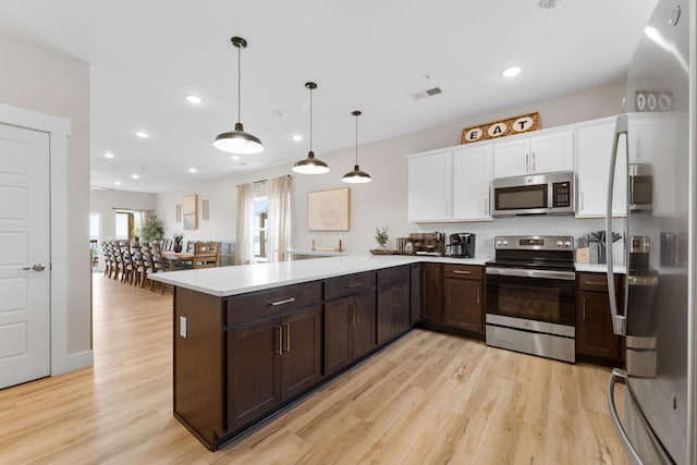 kitchen with pendant lighting, kitchen peninsula, light hardwood / wood-style flooring, white cabinetry, and stainless steel appliances