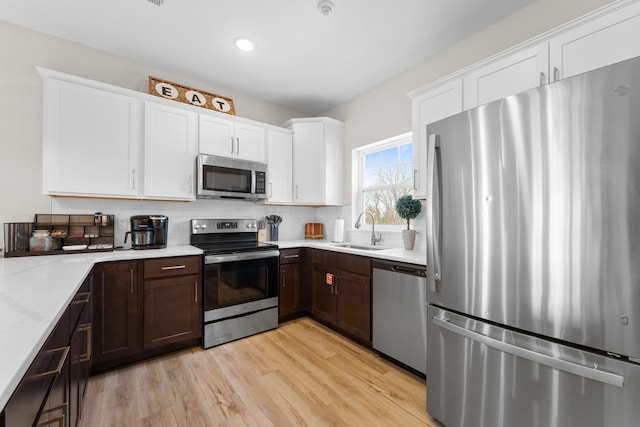 kitchen featuring stainless steel appliances, light hardwood / wood-style flooring, white cabinets, and sink