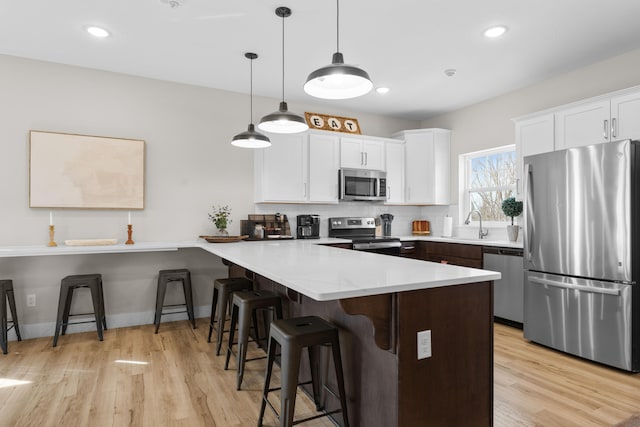 kitchen with white cabinets, stainless steel appliances, pendant lighting, and a kitchen bar