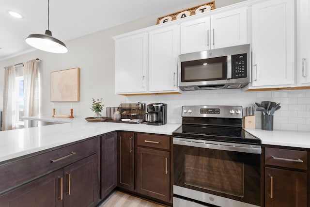 kitchen featuring decorative backsplash, stainless steel appliances, light hardwood / wood-style floors, white cabinetry, and decorative light fixtures