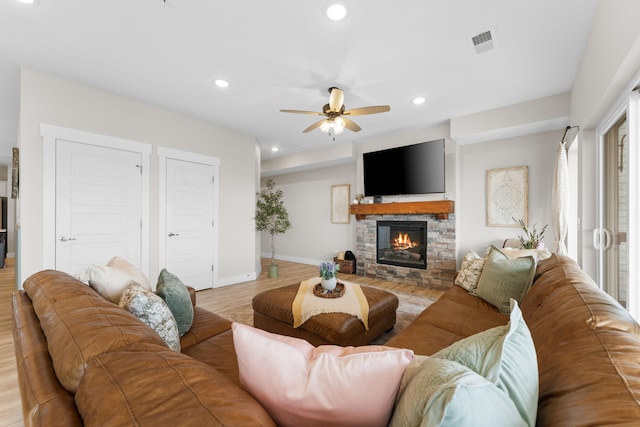 living room featuring a fireplace, ceiling fan, and light hardwood / wood-style flooring