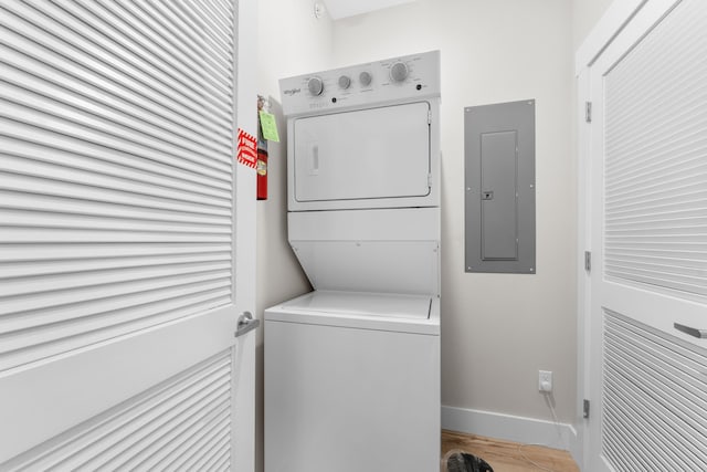 laundry area featuring electric panel and stacked washer / dryer