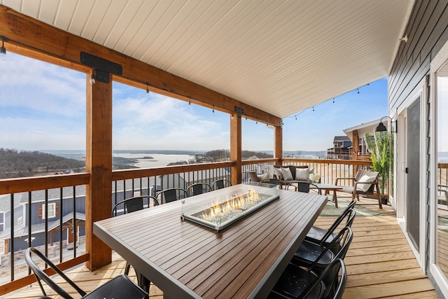 wooden deck with a water view and an outdoor living space with a fire pit