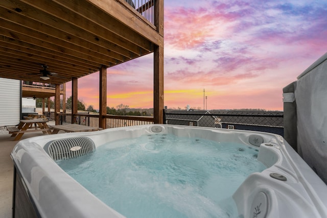 pool at dusk featuring a hot tub and ceiling fan