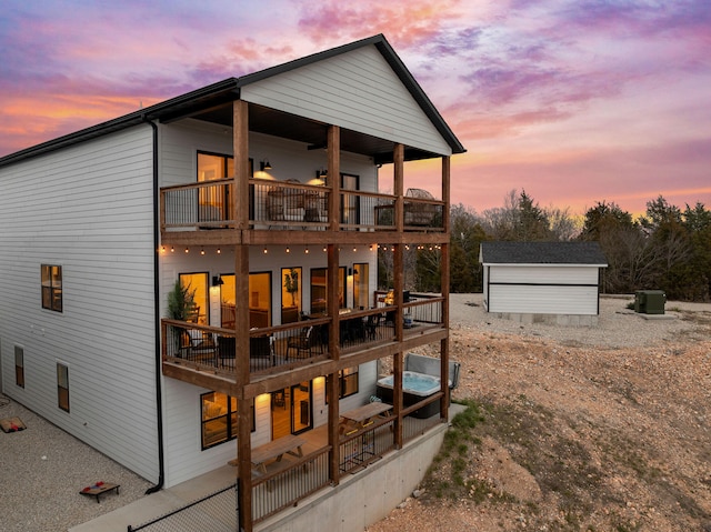 back house at dusk with a storage shed and a balcony