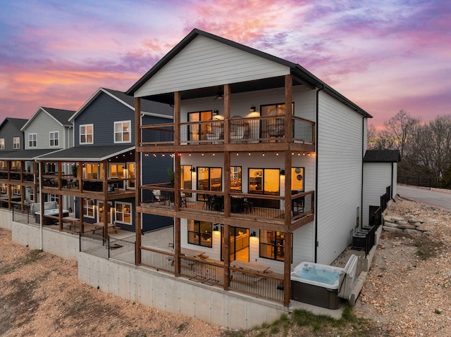 back house at dusk featuring a balcony and central AC