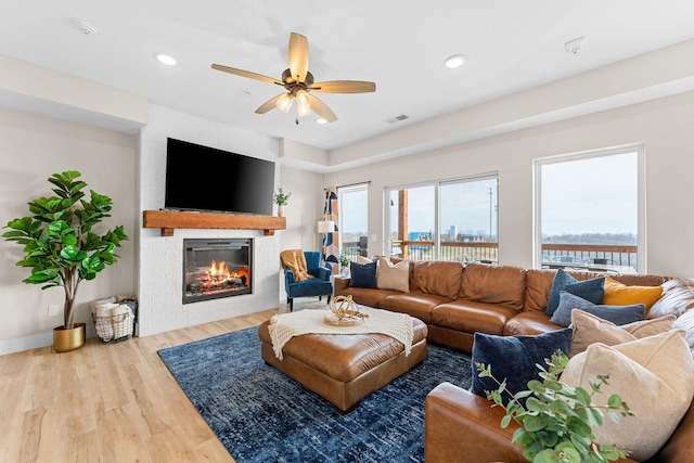 living room featuring a brick fireplace, ceiling fan, and hardwood / wood-style floors