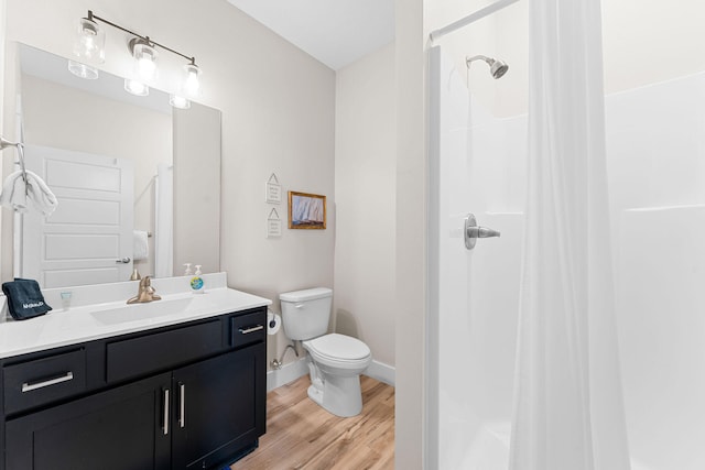 bathroom with hardwood / wood-style floors, toilet, walk in shower, and vanity