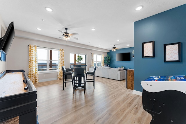 dining space featuring ceiling fan, light wood-type flooring, and a textured ceiling