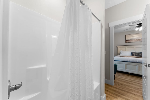 bathroom featuring hardwood / wood-style flooring, ceiling fan, and shower / bath combo