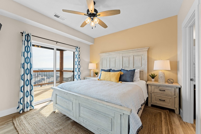 bedroom with ceiling fan, light hardwood / wood-style floors, access to exterior, and a water view