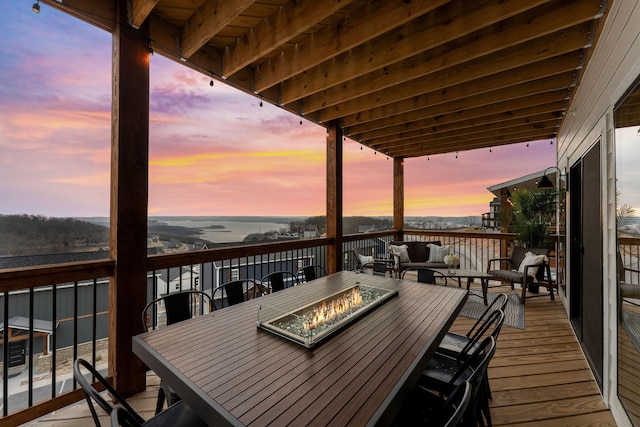 deck at dusk featuring a water view and an outdoor living space with a fire pit